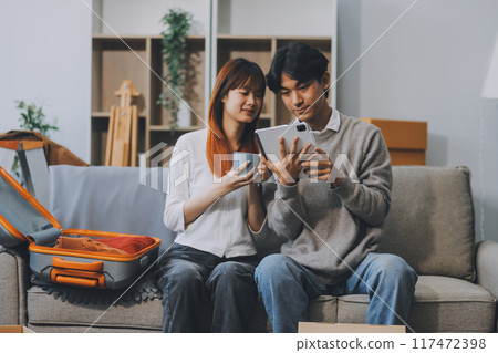 Young Asian couple relocating to a new house, joyfully packing and unpacking belongings. Expertise in moving, packing, togetherness, and creating a new home together. Young Asian couple relocating to a new house, joyfully packing and unpacking belongings. Expertise in moving, packing, togetherness, and creating a new home together. 117472398