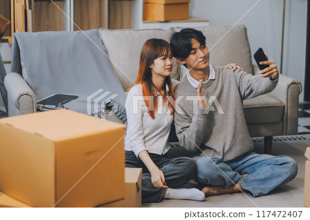 Young Asian couple relocating to a new house, joyfully packing and unpacking belongings. Expertise in moving, packing, togetherness, and creating a new home together. Young Asian couple relocating to a new house, joyfully packing and unpacking belongings. Expertise in moving, packing, togetherness, and creating a new home together. 117472407