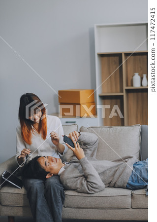 Happy asian young attractive couple man and woman sit on couch use tablet shopping online furniture decorate home in the living room at new house. Young married moving home shopper online concept. 117472415