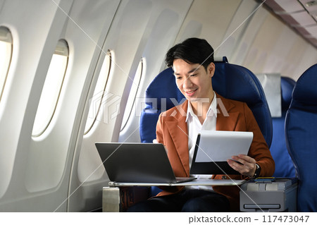 Professional businessman traveling by plane and working on his laptop. Business travel and transportation concept Professional businessman traveling by plane and working on his laptop. Business travel and transportation concept 117473047