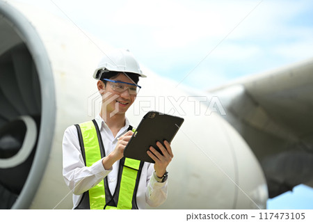 Young male engineer or aviation technician using digital tablet in front of large aircraft engine Young male engineer or aviation technician using digital tablet in front of large aircraft engine 117473105