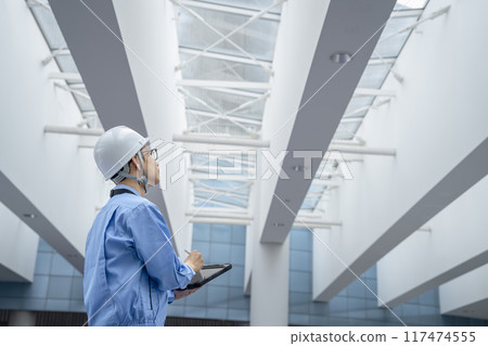 A man in work clothes holding a tablet. Image of building maintenance, construction management, inspection, and investigation. A man in work clothes holding a tablet. Image of building maintenance, construction management, inspection, and investigation. 117474555