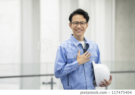 一個穿著工作服、戴著頭盔的男人看著相機，一張微笑的肖像 117475404