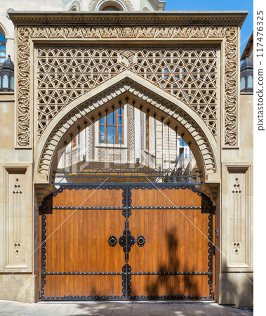 Intricately designed archway and wooden gate in a historic building during bright daylight 117476325