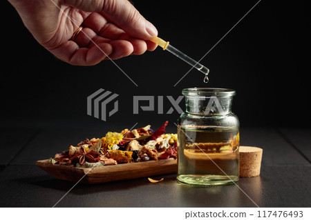 Dropping essential oil or herbal tincture into a small bottle. 117476493