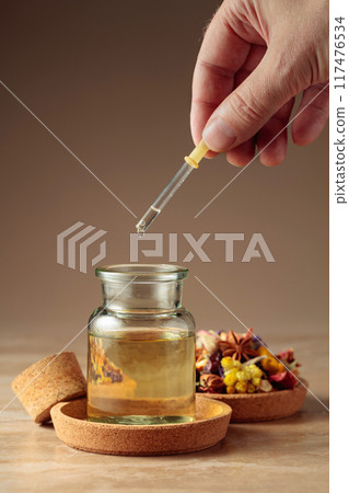 Dropping essential oil or herbal tincture into a glass bottle. 117476534