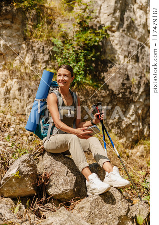 A woman enjoying hiking with her backpack amidst the beauty of nature and greenery A woman enjoying hiking with her backpack amidst the beauty of nature and greenery 117479182