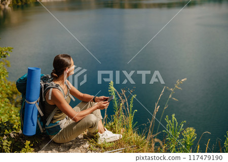 A Serene Hiker Enjoying the Peacefulness of a Tranquil Lake Surrounded by Natures Beauty 117479190