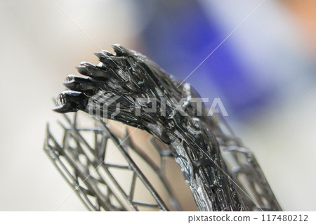 Model of leg printed on a 3D printer from black rubber, close-up. Part of an object created on a 3D printer from hardened rubber under the influence of ultraviolet light. SLA 3D printing technology. 117480212