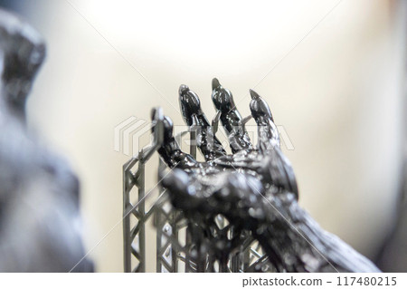 Model of hand printed on a 3D printer from black rubber, close-up. Part of an object created on a 3D printer from hardened rubber under the influence of ultraviolet light. SLA 3D printing technology. 117480215