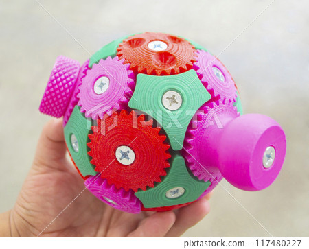 A person holding in his hand an object printed on a 3D printer. Geometric model printed on a 3D printer from molten plastic close-up. Multi-colored shape created by 3D printer. FDM technology. A person holding in his hand an object printed on a 3D printer. Geometric model printed on a 3D printer from molten plastic close-up. Multi-colored shape created by 3D printer. FDM technology. 117480227