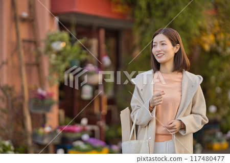 A middle-aged woman wearing a half coat going shopping A middle-aged woman wearing a half coat going shopping 117480477
