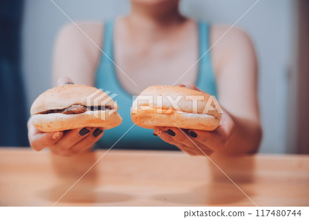 Binge eating disorder concept with woman eating fast food burger, fired chicken , donuts and desserts 117480744
