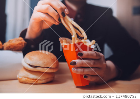 Asian woman holding french fries and eating happily in restaurant 117480752