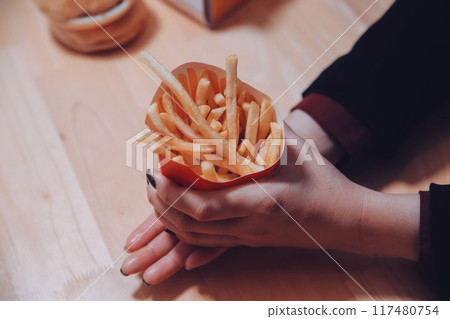 Asian woman holding french fries and eating happily in restaurant 117480754