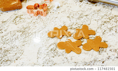Using various festive cookie cutters, we're cutting out charming gingerbread cookies from the rolled dough on the sleek marble counter, bringing holiday cheer to the modern kitchen. Using various festive cookie cutters, we're cutting out charming gingerbread cookies from the rolled dough on the sleek marble counter, bringing holiday cheer to the modern kitchen. 117481501