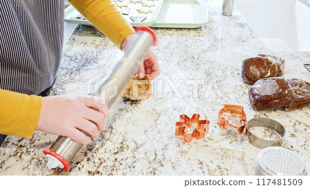 Using an adjustable rolling pin to roll out gingerbread cookie dough on the elegant marble counter in a modern kitchen, getting ready for festive holiday baking. 117481509