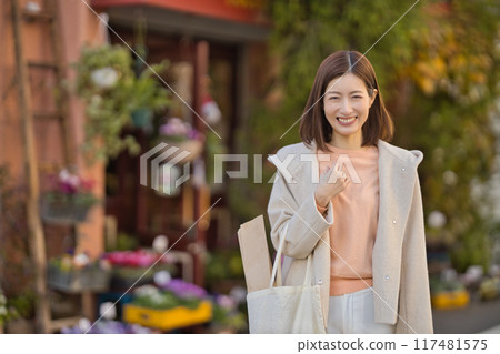 A middle-aged woman wearing a half coat going shopping 117481575