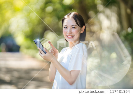 Young woman looking at her smartphone in the sunlight 117481594