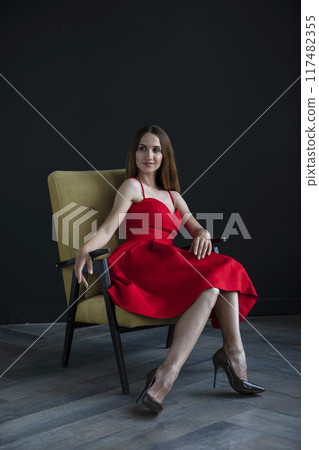 portrait of a beautiful young woman in a red dress, studio shot on a dark background 117482355