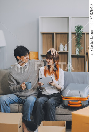 Young Asian couple relocating to a new house, joyfully packing and unpacking belongings. Expertise in moving, packing, togetherness, and creating a new home together. Young Asian couple relocating to a new house, joyfully packing and unpacking belongings. Expertise in moving, packing, togetherness, and creating a new home together. 117482649