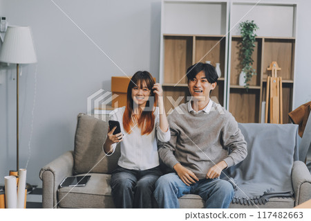 Happy asian young attractive couple man and woman sit on couch use tablet shopping online furniture decorate home in the living room at new house. Young married moving home shopper online concept. Happy asian young attractive couple man and woman sit on couch use tablet shopping online furniture decorate home in the living room at new house. Young married moving home shopper online concept. 117482663