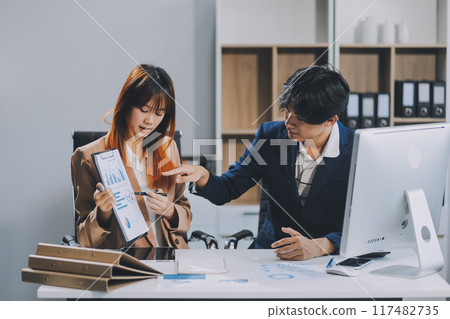 Entrepreneur Asian businessman and businesswoman discussing new business project in tablet in modern Meeting In Modern Office, Asian business casual concept. 117482735
