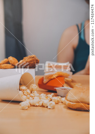 fast food, people and unhealthy eating concept - close up of woman hands holding hamburger or cheeseburger 117484474