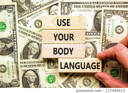Use your body language symbol. Concept words Use your body language on wooden block. Beautiful background from dollar bills. Motivational business use your body language concept. Copy space. 117484613