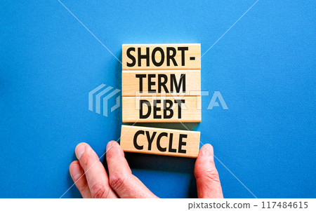 Short-term debt cycle symbol. Concept words Short-term debt cycle on beautiful wooden block. Beautiful blue table background. Businessman hand. Business Short-term debt cycle concept. Copy space. 117484615