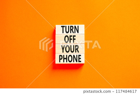 Turn off your phone symbol. Concept words Turn off your phone on wooden blocks. Beautiful orange table orange background. Business, psychological turn off your phone concept. Copy space. Turn off your phone symbol. Concept words Turn off your phone on wooden blocks. Beautiful orange table orange background. Business, psychological turn off your phone concept. Copy space. 117484617