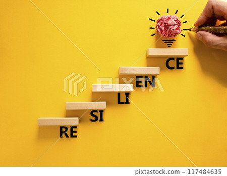 Resilience symbol. Concept word Resilience on beautiful wooden blocks. Beautiful yellow background. Businessman hand. Beautiful light bulb icon. Business resilience concept. Copy space. 117484635