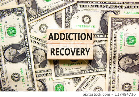 Addiction recovery symbol. Concept words Addiction recovery on beautiful wooden blocks. Dollar bills. Beautiful background from dollar bills. Psychology addiction recovery concept. Copy space. 117484730