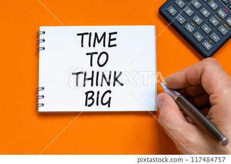 Time to think big symbol. Concept words Time to think big on beautiful white note. Beautiful orange background. Businessman hand. Calculator. Business and time to think big concept. Copy space. Time to think big symbol. Concept words Time to think big on beautiful white note. Beautiful orange background. Businessman hand. Calculator. Business and time to think big concept. Copy space. 117484757