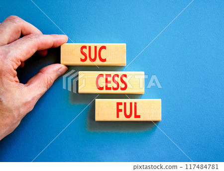 Successful symbol. Concept word Successful on beautiful wooden blocks. Businessman hand. Beautiful blue background. Business successful concept. Copy space. Successful symbol. Concept word Successful on beautiful wooden blocks. Businessman hand. Beautiful blue background. Business successful concept. Copy space. 117484781