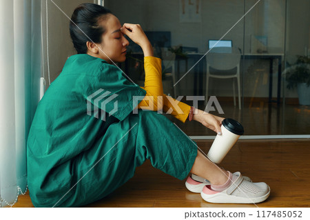 Meditating Woman Sitting by Window Holding Tumbler Meditating Woman Sitting by Window Holding Tumbler 117485052