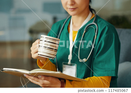 Portrait of Nurse Drinking from Mug and Reading Notebook Portrait of Nurse Drinking from Mug and Reading Notebook 117485067