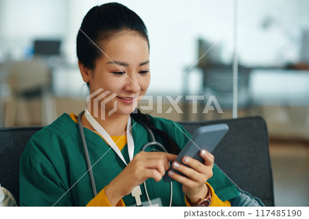 Smiling Nurse Using Smartphone in Hospital Setting Smiling Nurse Using Smartphone in Hospital Setting 117485190
