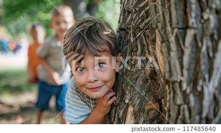 Young boys and girls playing hide and seek in park, with kid counting leaning on tree 117485640
