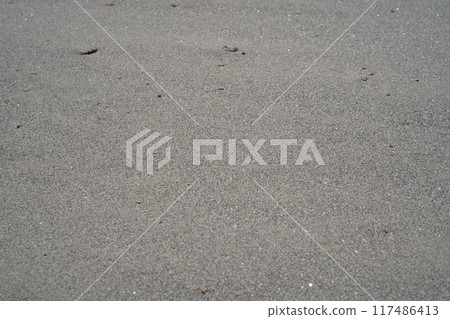 Grey sand, natural background. Photo of grey sand with sharpness in the centre and blurring to the edges. Details, texture close-up, copy space. 117486413