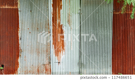 An image of corrugated zinc with rust patches, displaying the textured surface and weathered appearance. 117486651