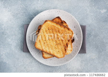 Bread toast crispy for sandwiches on a plate on a gray concrete table. Copy space. Bread toast crispy for sandwiches on a plate on a gray concrete table. Copy space. 117486662