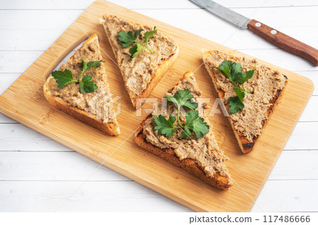 Sandwiches crispy toast and chicken liver pate with parsley leaves on a wooden cutting board. Copy space. 117486666