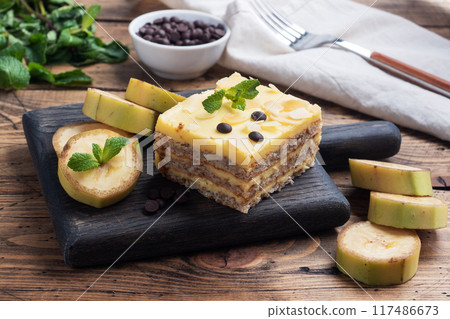 Banana sponge cake with nuts and chocolate drops. Delicious sweet dessert for tea, wooden background. top view, copy space. Banana sponge cake with nuts and chocolate drops. Delicious sweet dessert for tea, wooden background. top view, copy space. 117486673