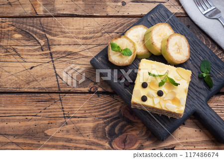 Banana sponge cake with nuts and chocolate drops. Delicious sweet dessert for tea, wooden background. top view, copy space. Banana sponge cake with nuts and chocolate drops. Delicious sweet dessert for tea, wooden background. top view, copy space. 117486674
