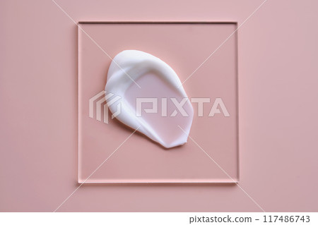 A smear of white cream on a square transparent stand on a pink background. A smear of white cream on a square transparent stand on a pink background. 117486743