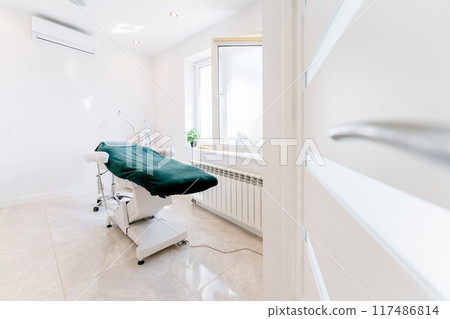 Stylish room interior with massage table in BEAUTY salon. A medical office with a green table and white walls. 117486814