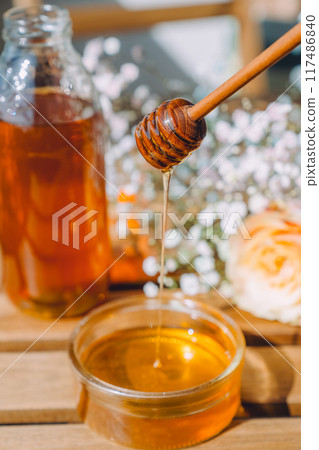 Golden honey dripping from a honey dipper Golden honey dripping from a honey dipper 117486840