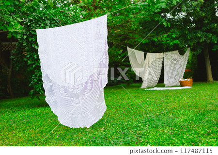 White laundry on clothesline in garden. White curtains drying in the sun. 117487115