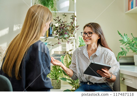 Professional mental therapist working with young woman, sitting together in office 117487118